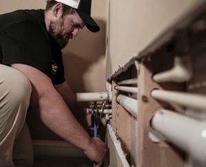 Plumber repairing pipes inside a wall