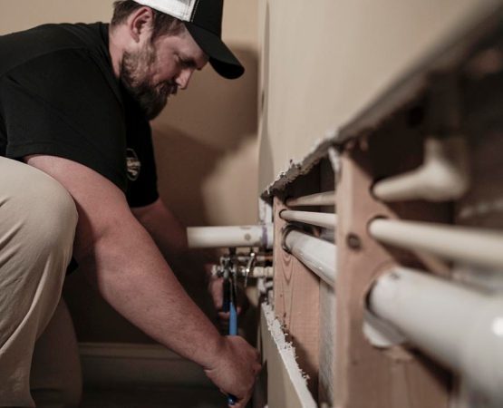 Plumber repairing pipes inside a wall